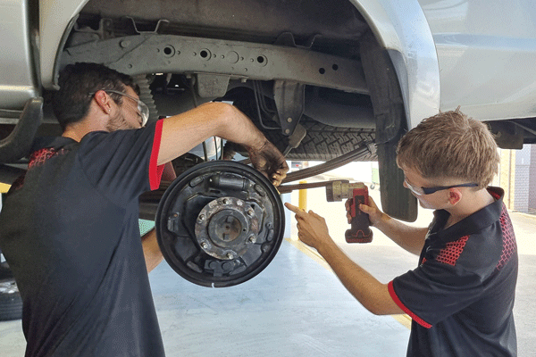 Phoenix and Daryn working together on a hoisted car